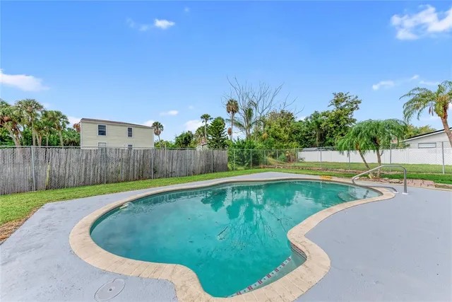 a view of a swimming pool with a yard and wooden fence
