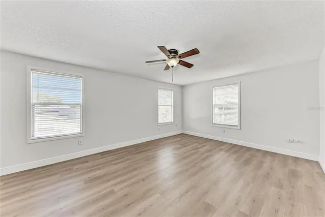 a view of an empty room with a window and a ceiling fan