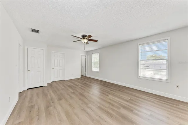 a view of an empty room with a window and wooden floor