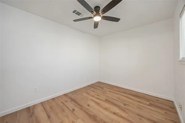 an empty room with a fan & a ceiling fan