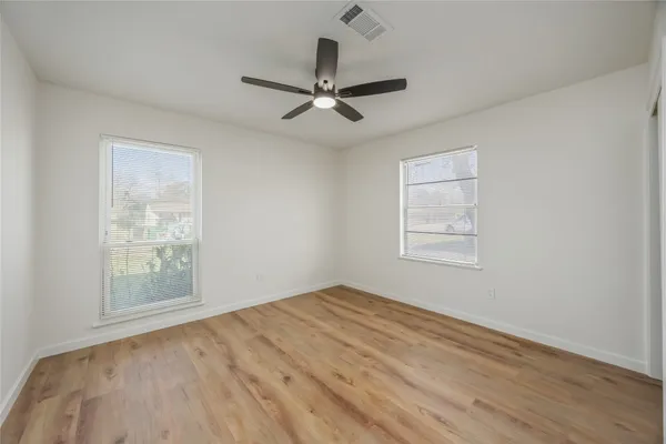 a view of empty room with wooden floor and fan