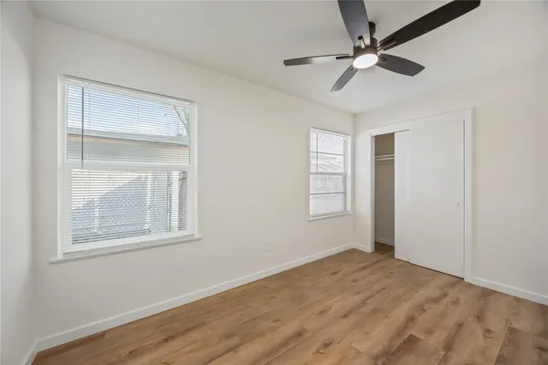a view of empty room with wooden floor and fan