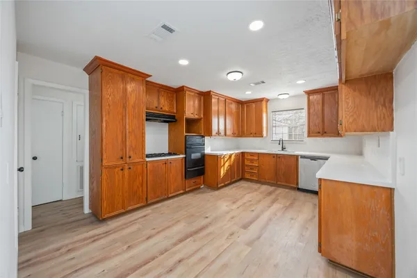 a large kitchen with wooden floors and stainless steel appliances