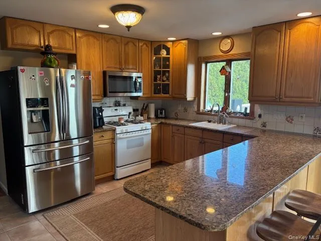 a kitchen with stainless steel appliances granite countertop a refrigerator a sink a stove a washer dryer and cabinets
