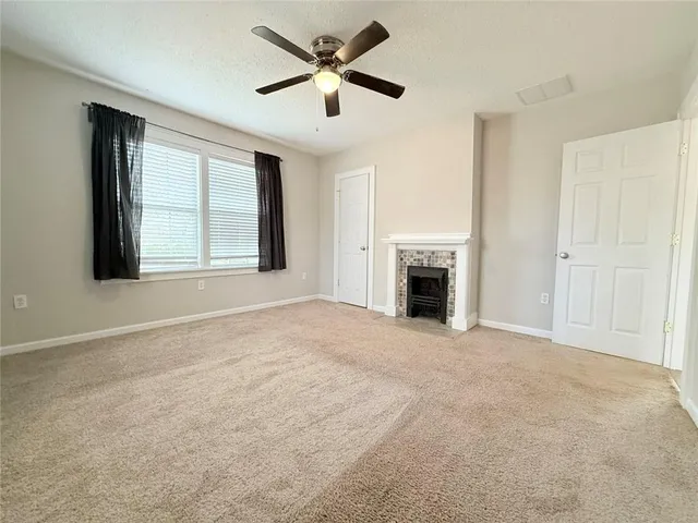 an empty room with chandelier fan and windows
