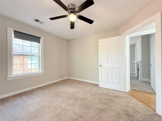 a view of a livingroom with a ceiling fan & windows