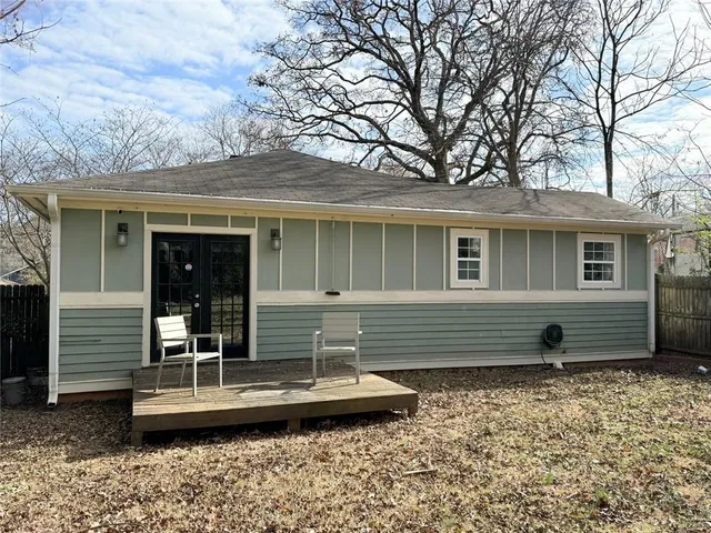 a view of a house with a large tree and covered with wooden fence