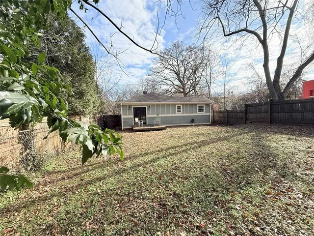 a backyard of a house with large trees and wooden fence