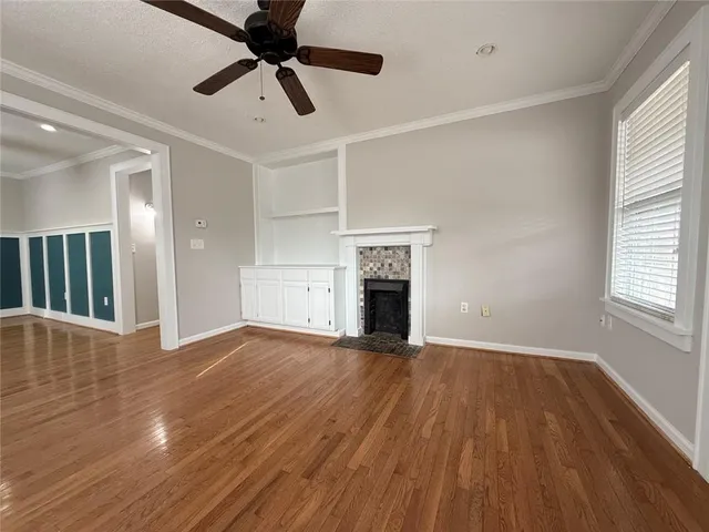a view of an empty room with wooden floor and a fireplace