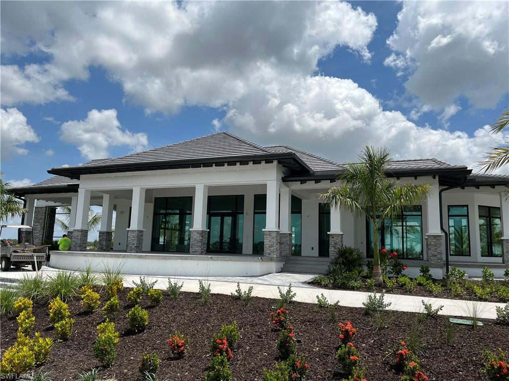 4580 Centaurus Circle Naples, FL 34120 - Photo 22 of 25 Back of house with stone siding, stucco siding, a tiled roof, and covered porch