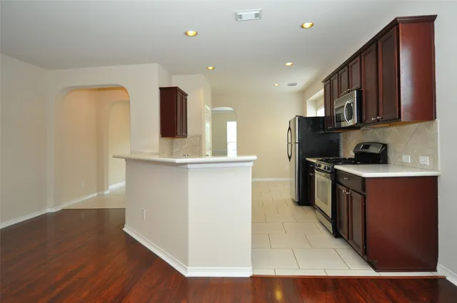 a kitchen with stainless steel appliances granite countertop a refrigerator a stove and a wooden floors