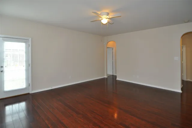 a view of empty room with wooden floor and fan