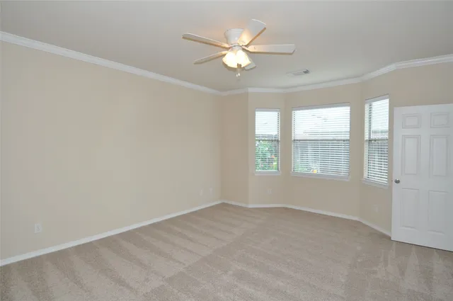an empty room with windows and ceiling fan