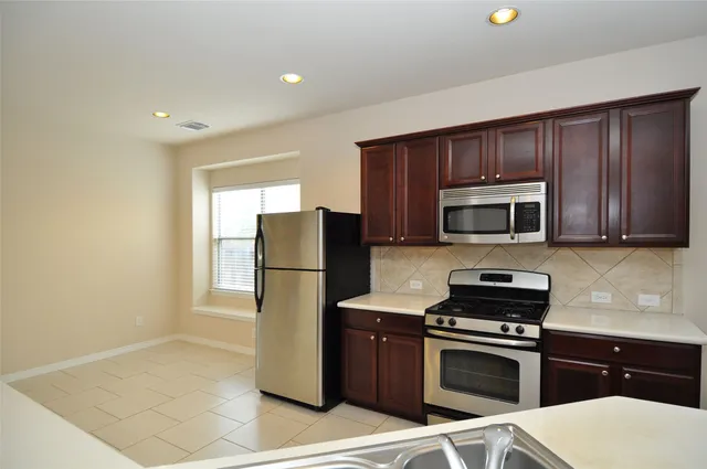 a kitchen with stainless steel appliances a refrigerator a stove a microwave and cabinets