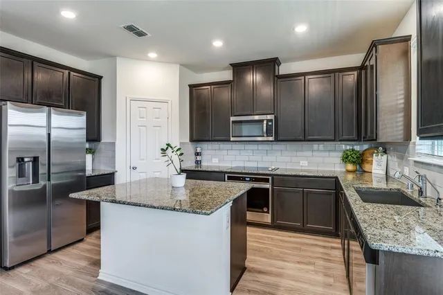 a kitchen with stainless steel appliances granite countertop a sink stove and refrigerator