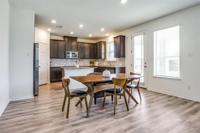 a dining room with stainless steel appliances granite countertop wooden floor a table and chairs