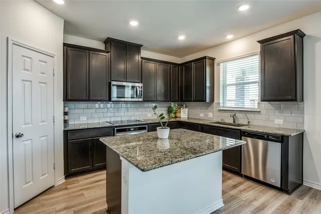 a kitchen with kitchen island granite countertop stainless steel appliances a sink stove and refrigerator