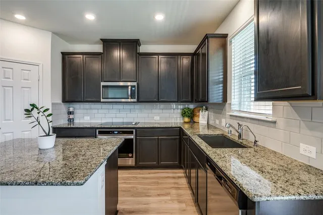 a kitchen with stainless steel appliances granite countertop a sink stove and refrigerator