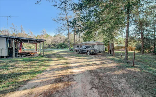 a view of a house with truck parked on a road next to a yard