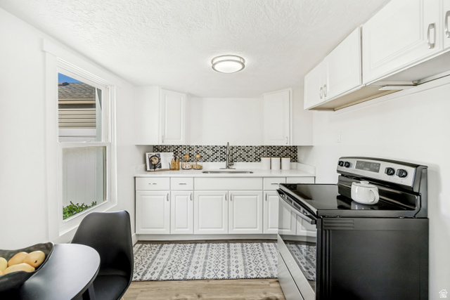 712 9th Street Ogden, UT 84404 - Photo 3 of 15 Contemporary kitchen featuring white cabinetry, quartz countertops, a mosaic tile backsplash, and wood-finish flooring
