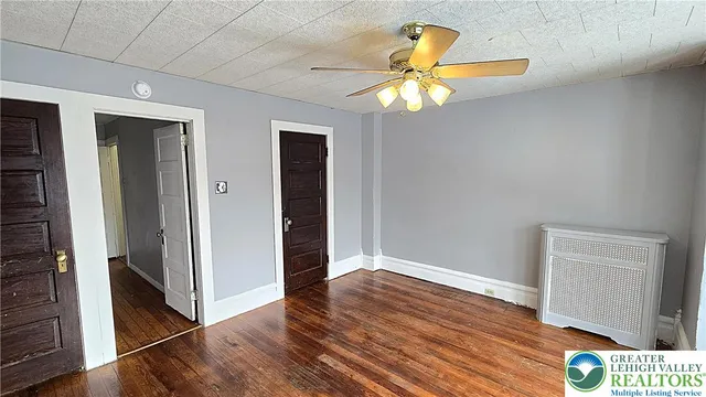 an empty room with wooden floor and a ceiling fan