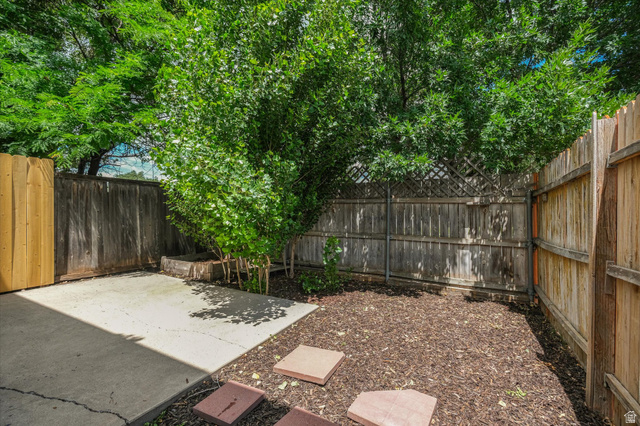 187 West 1190th Street North Logan, UT 84341 - Photo 9 of 12 Private outdoor space featuring concrete patio, wood fencing, stepping stones, and mature trees