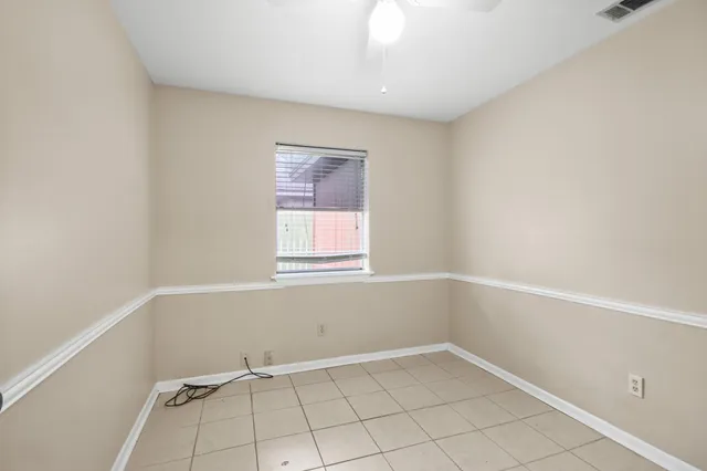 an empty room with ceiling fan and window