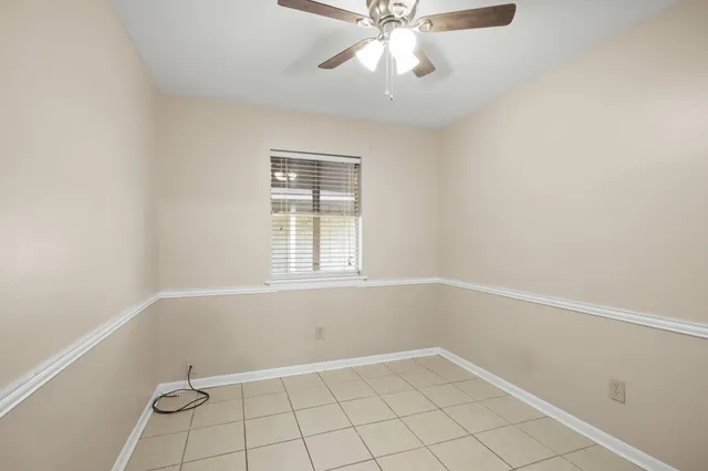 a view of an empty room with window and chandelier fan