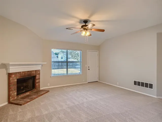 a view of an empty room with window and fireplace