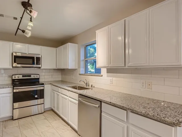 a kitchen with granite countertop white cabinets stainless steel appliances and a sink