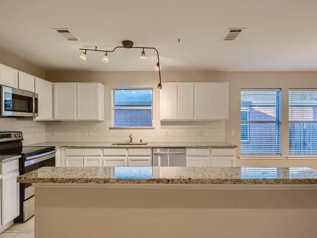 a kitchen with granite countertop a sink stainless steel appliances and cabinets