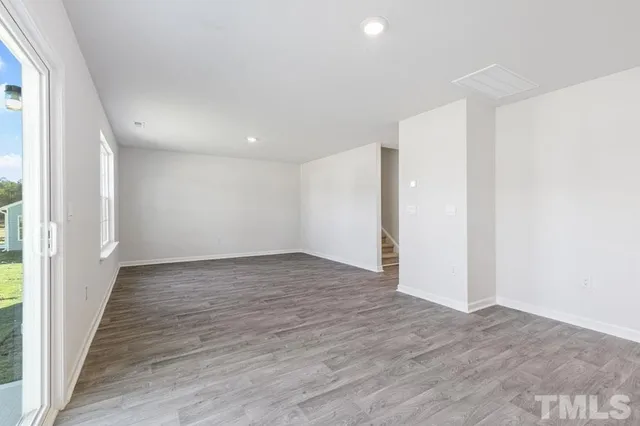 a view of an empty room with window and wooden floor