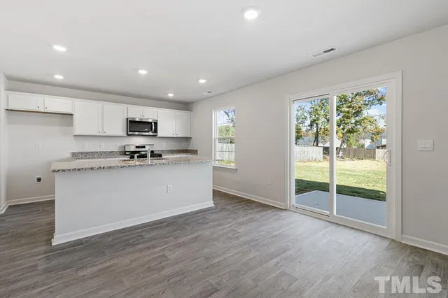 a kitchen with granite countertop white cabinets and black stainless steel appliances