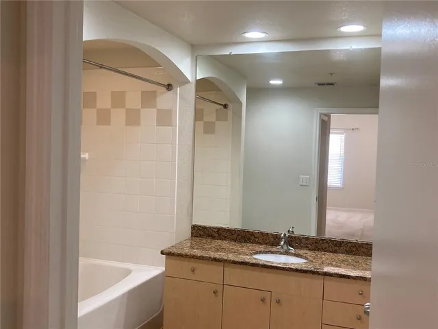 a bathroom with a granite countertop sink a mirror and a bathtub