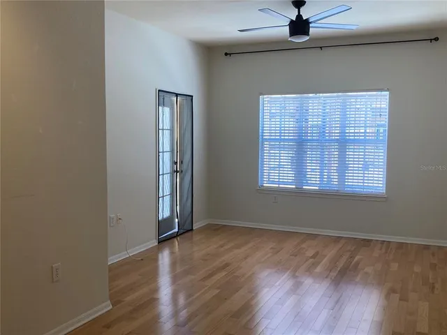 an empty room with wooden floor cabinet and windows