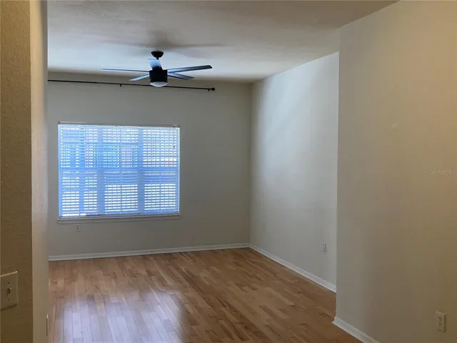 a view of an empty room with wooden floor and a window