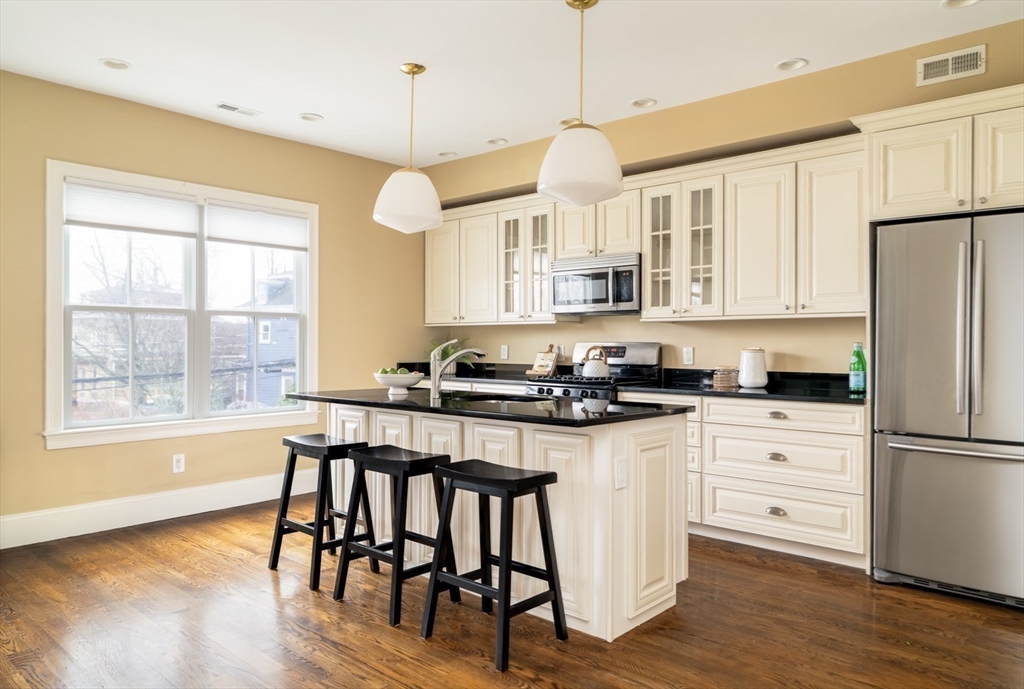 291 Lamartine Street, Unit 2 Boston, MA 02130 - Photo 3 of 18 a kitchen with stainless steel appliances granite countertop a stove a refrigerator a kitchen island a island a stove a cabinets and chairs with wooden floor