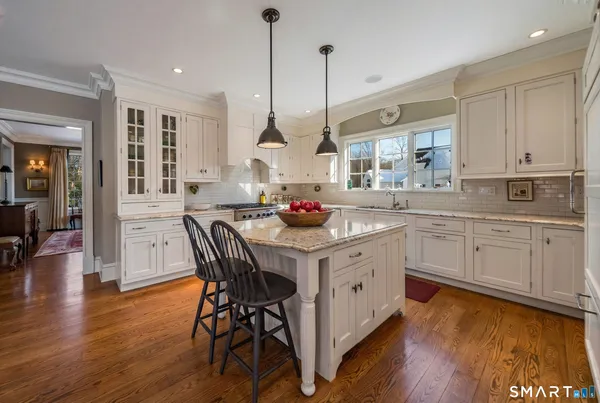 a kitchen with stainless steel appliances granite countertop a stove a sink dishwasher a dining table and chairs with wooden floor