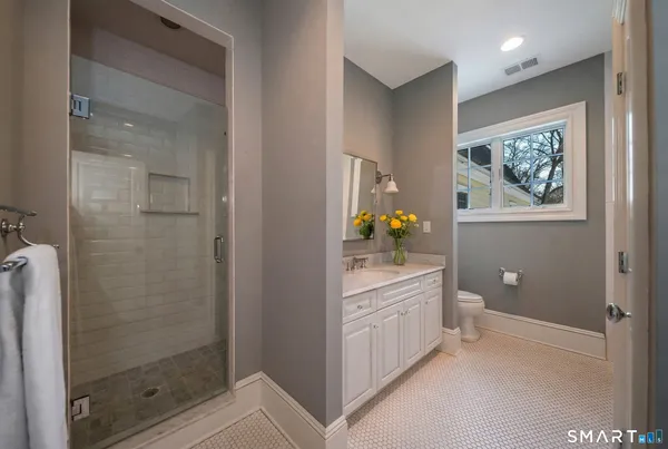 a bathroom with a granite countertop sink a toilet and shower