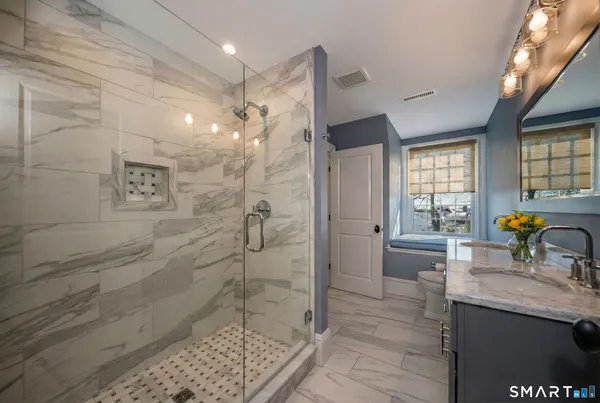 a bathroom with a granite countertop sink a mirror and a shower