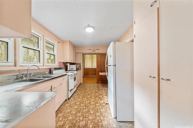 a large white kitchen with a sink and dishwasher a refrigerator with wooden floor