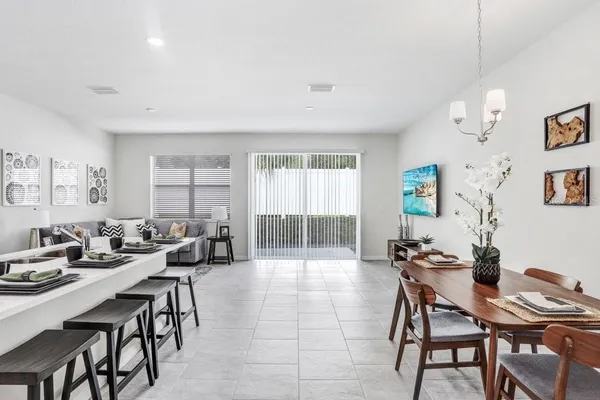 a view of a dining room and livingroom with furniture wooden floor a rug a painting and a chandelier