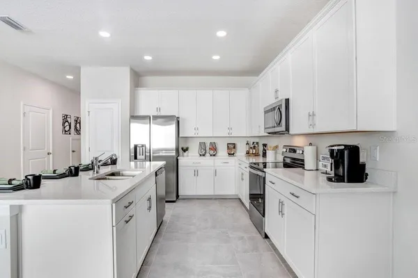 a kitchen with white cabinets sink and stove