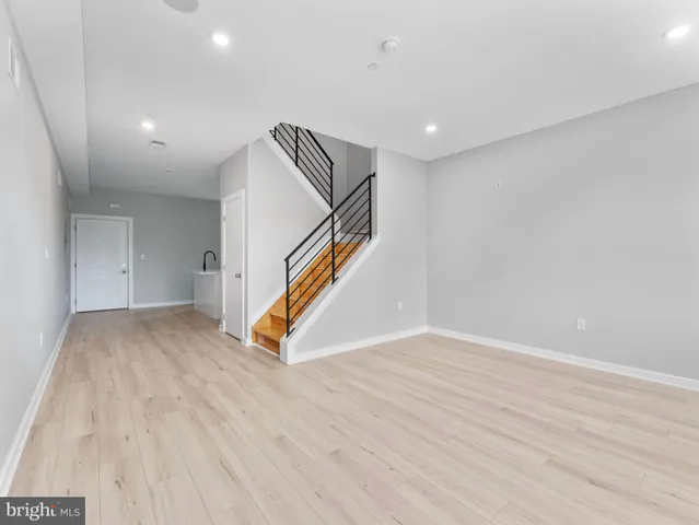 a view of an empty room with wooden floor and staircase