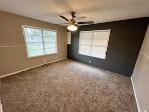 en empty room with windows and ceiling fan