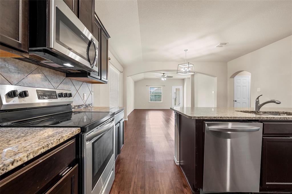 3217 Beutel Road Lorena, TX 76655 - Photo 12 of 40 Kitchen with stainless steel appliances, arched walkways, decorative backsplash, dark wood-type flooring, and ceiling fan