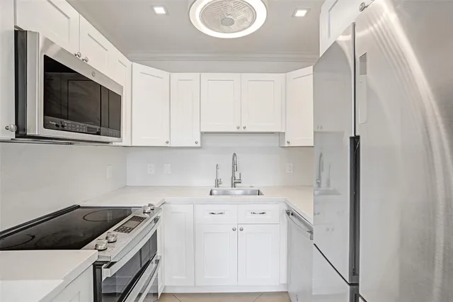 a kitchen with white cabinets stainless steel appliances and sink