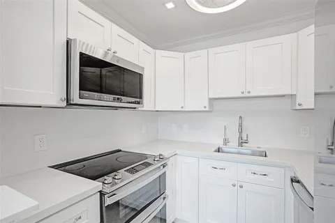 a kitchen with stainless steel appliances white cabinets and a refrigerator