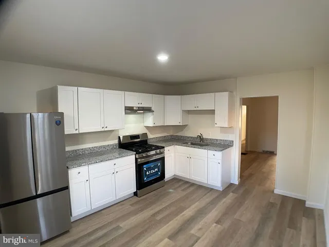 a kitchen with granite countertop a refrigerator stove top oven and sink