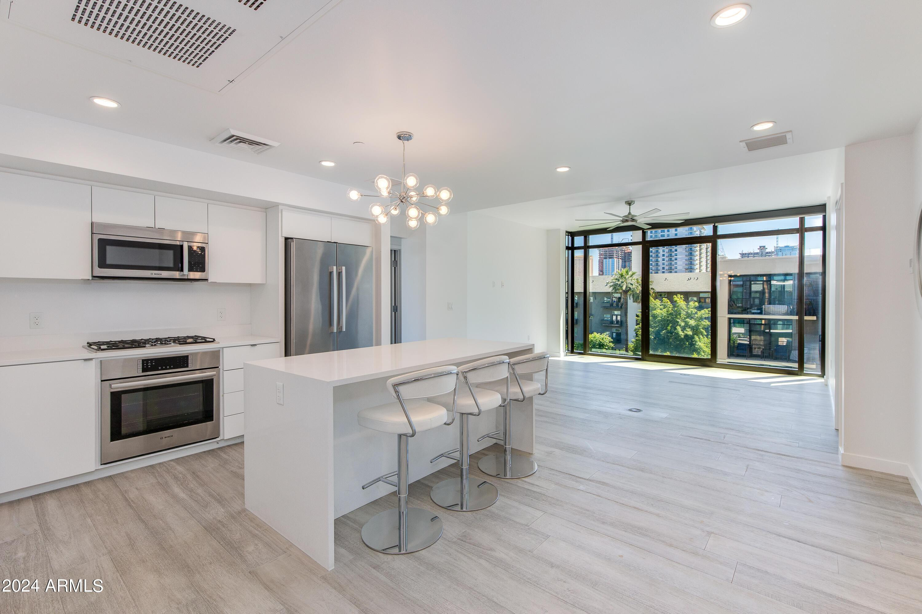 a large white kitchen with granite countertop a stove and a wooden floor